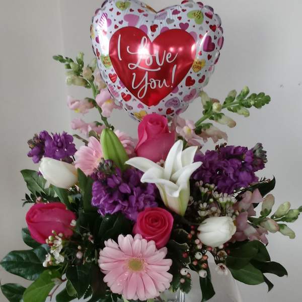 Mixed flower arrangement with a heart-shaped "I Love You" balloon in a glass vase