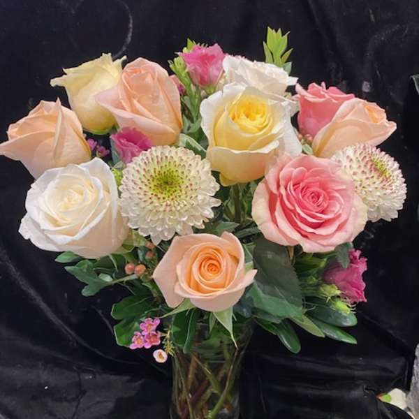 Bouquet of pastel roses and white chrysanthemums in a glass vase