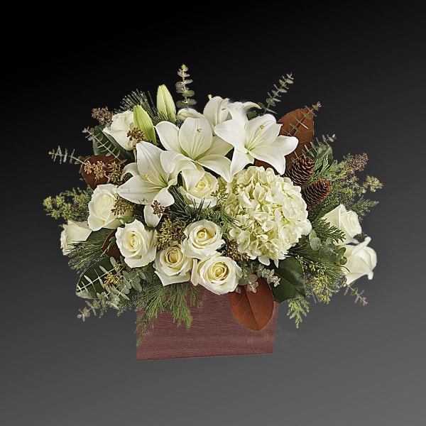 White lilies and roses arranged in a wooden box with pinecones