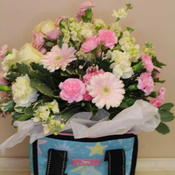 Pink and white mixed flower bouquet in a decorative tote bag