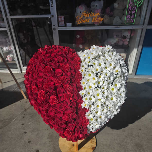 Heart-shaped floral arrangement with red roses and white daisies
