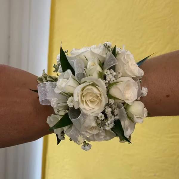 White rose wrist corsage with silver ribbon on a person's wrist