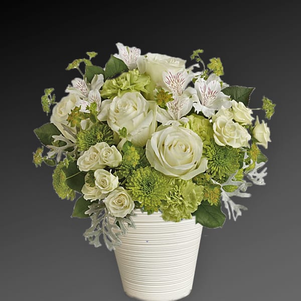 White and green floral arrangement in a ribbed white vase