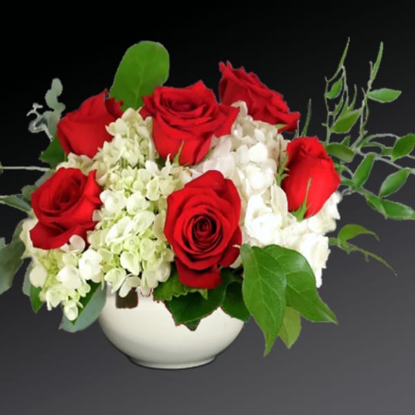 Red roses and white hydrangeas in a white bowl vase