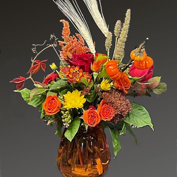 Autumn bouquet of orange and yellow flowers in an amber glass vase