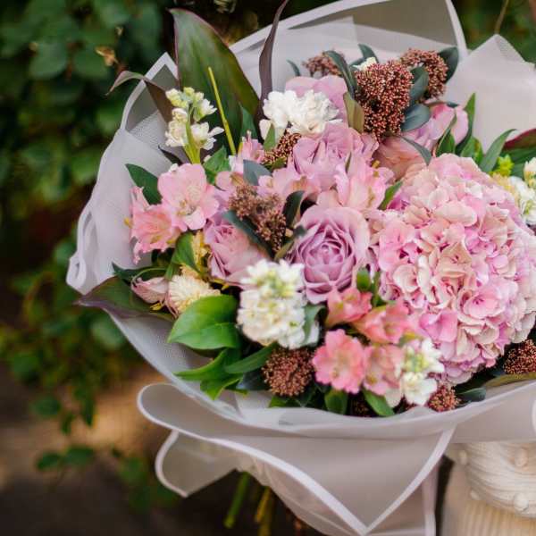 Pink and lavender bouquet with hydrangea and roses wrapped in white paper