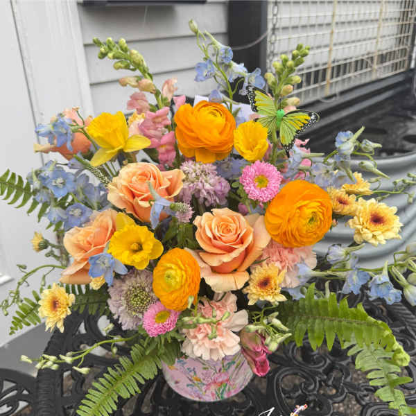 Colorful mixed bouquet in a floral tin with roses and daisies
