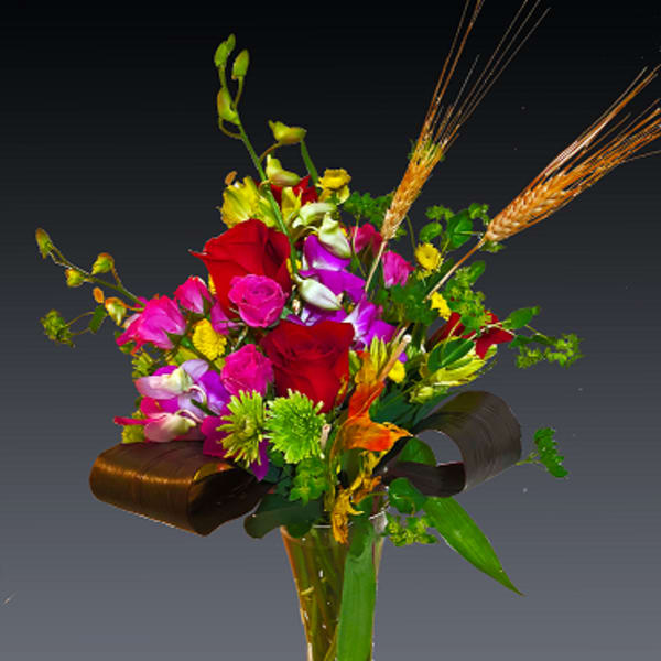 Mixed bouquet of red, pink, and purple flowers in a clear glass vase