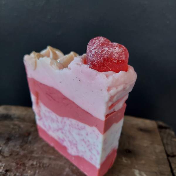 Pink layered soap bar topped with a red heart-shaped candy