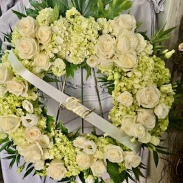 White floral wreath with roses and pale green blooms on a stand