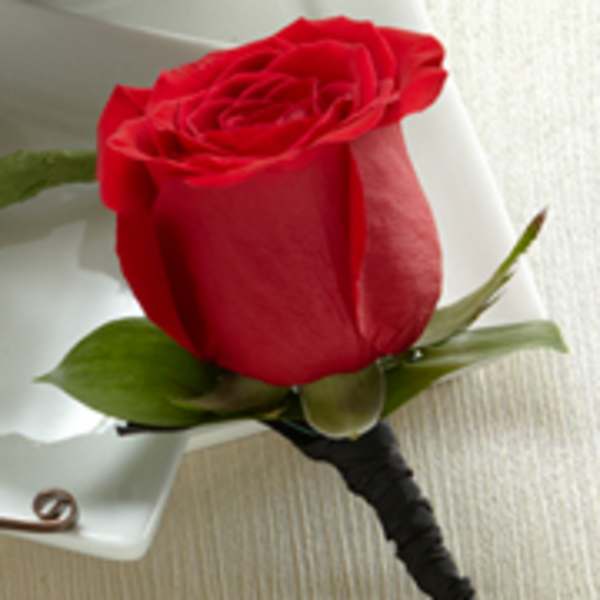 Single red rose boutonniere with black wrapped stem on a white surface