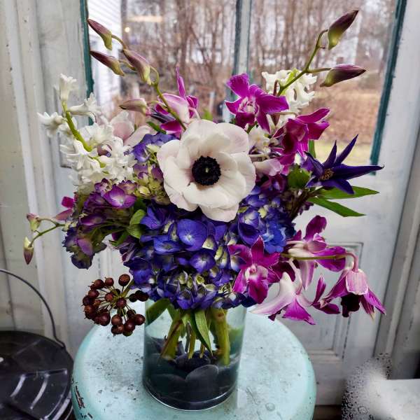 Bouquet of purple, white, and blue flowers in a glass vase