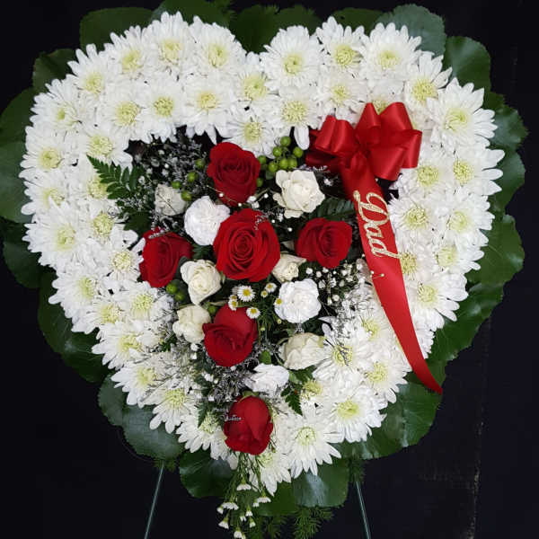 Heart-shaped floral wreath with white daisies and red roses, accented by a red ribbon