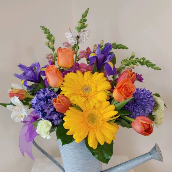 Colorful bouquet in a watering can with yellow daisies and orange roses