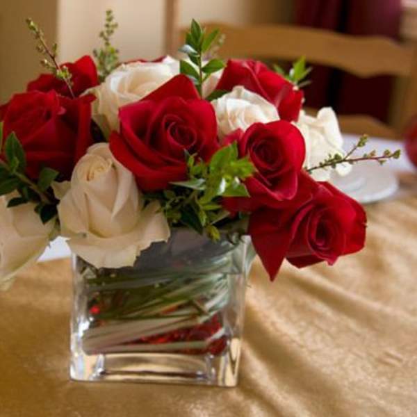 Red and white roses arranged in a clear square glass vase