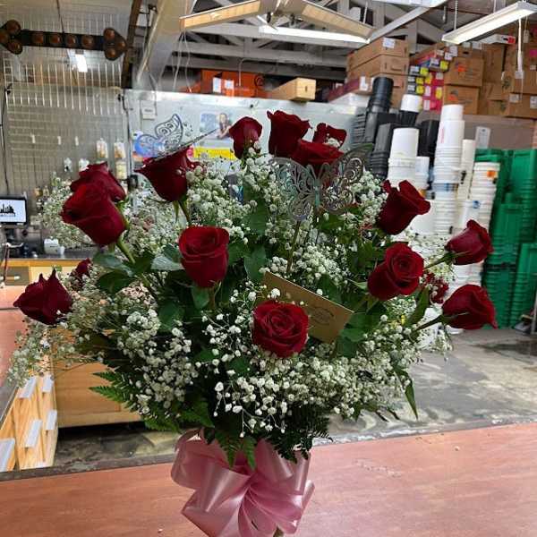 Bouquet of red roses and baby's breath in a glass vase with a pink ribbon