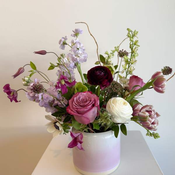 Mixed pink, white, and lavender flowers in a white vase