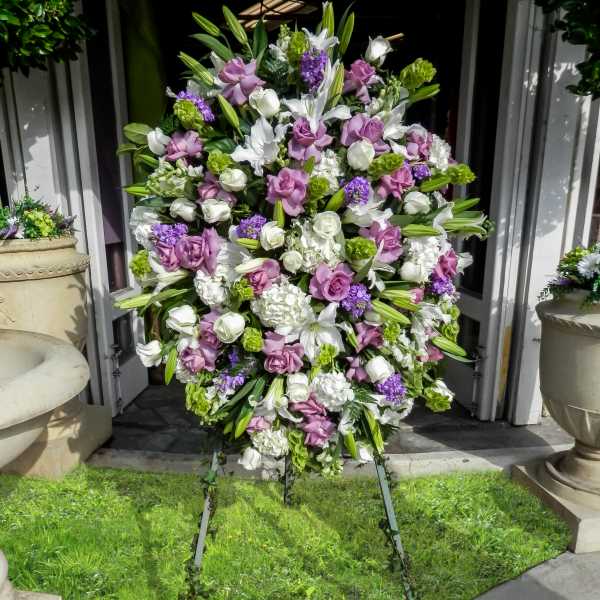 Large standing floral spray with white, lavender, and green blooms