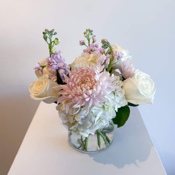 Pink and white flowers arranged in a clear glass vase