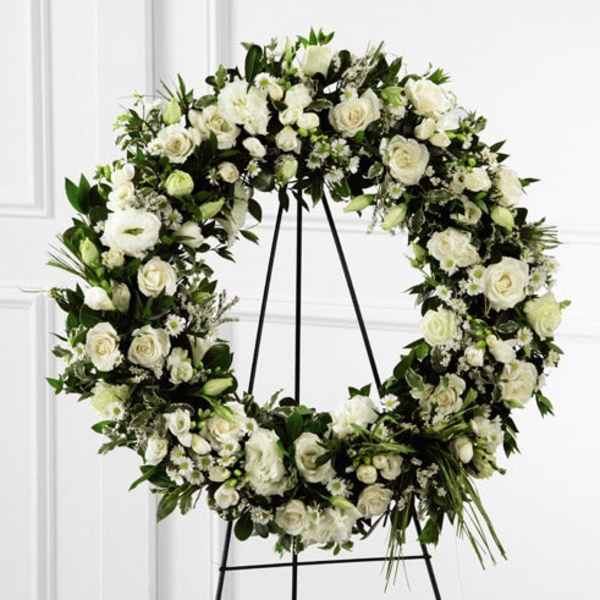 Large white floral wreath on a black stand