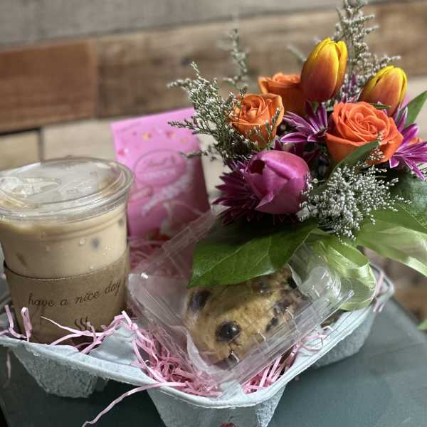 Gift set with iced coffee, cookies, and a small orange and pink flower arrangement in a drink carrier.