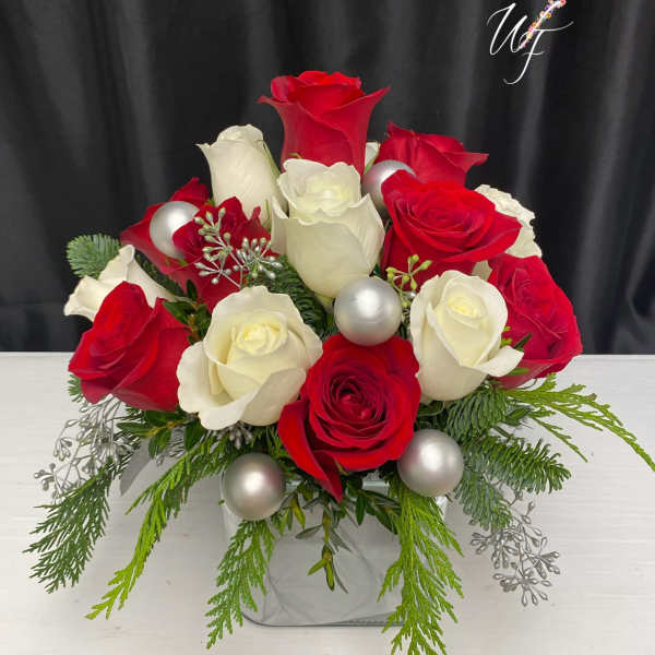 Red and white roses arranged in a square vase with silver ornaments