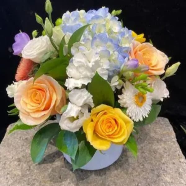 Mixed bouquet with pastel roses, hydrangea, and daisies in a round vase