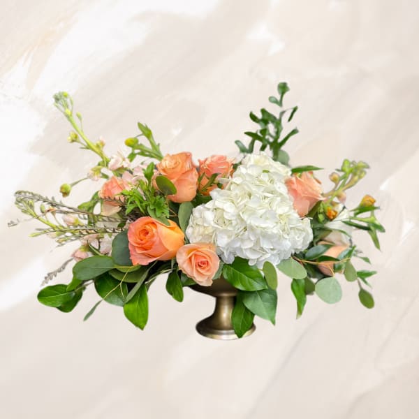 Peach roses and white hydrangea in a low pedestal vase
