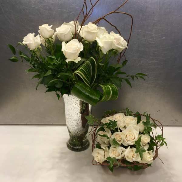 White rose arrangements in a vase and basket with curly branches