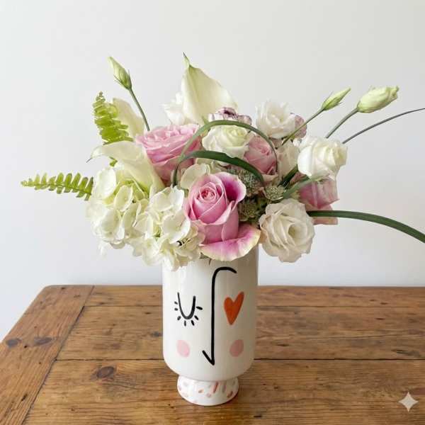 Pink and white roses arranged in a painted ceramic vase