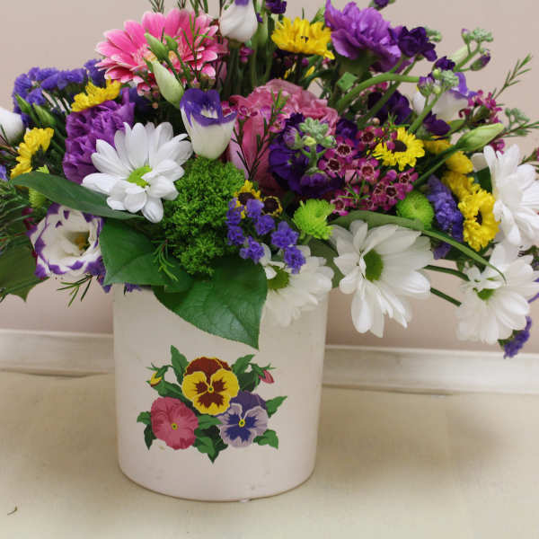 Mixed bouquet in a white ceramic pot with white, purple, pink, and yellow flowers