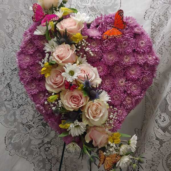 Heart-shaped floral arrangement with pink roses and purple blooms