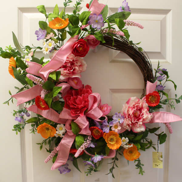 Floral wreath with pink ribbon and mixed orange, red, purple, and pink flowers