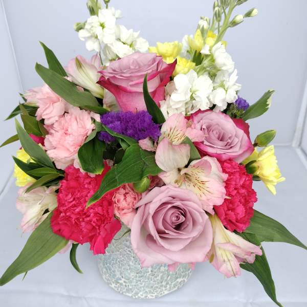Mixed bouquet of pink and white flowers in a textured vase