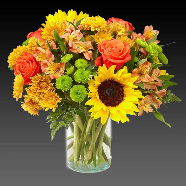Bouquet of sunflowers, orange roses, and yellow mums in a glass vase