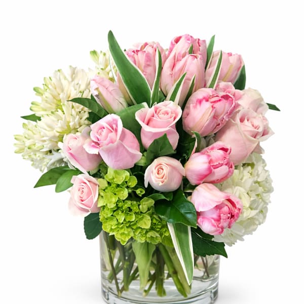 Pink roses and tulips arranged in a clear glass vase