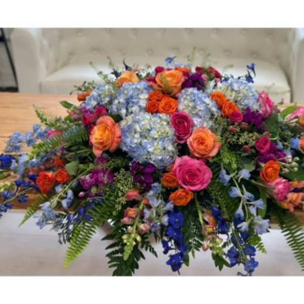 Large colorful floral centerpiece with roses and blue hydrangeas on a table