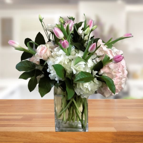 Pink tulips and pale hydrangeas in a clear glass vase