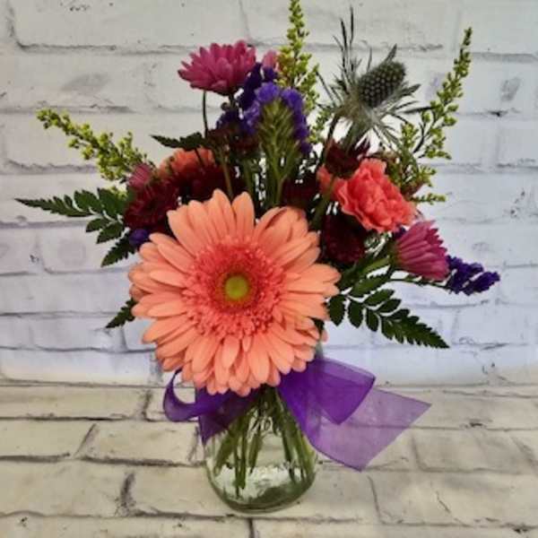 Mixed bouquet with a peach gerbera daisy in a glass vase