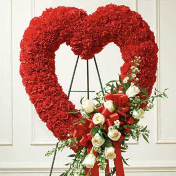 Heart-shaped red floral wreath with white roses and a red ribbon bow