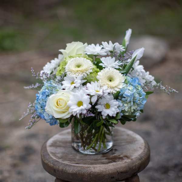 White and blue flower arrangement in a clear glass vase