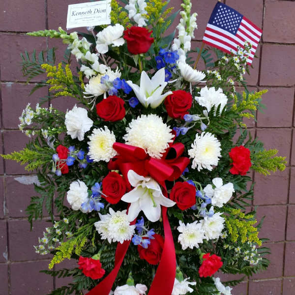 Standing floral spray with red roses, white lilies, and an American flag