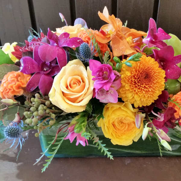 Colorful mixed flower arrangement in a rectangular glass vase