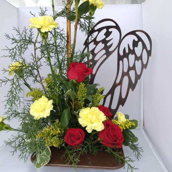Red roses and yellow carnations arranged with angel wings