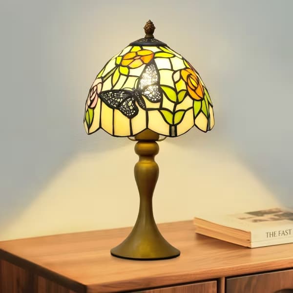 Stained-glass table lamp with butterfly and floral shade on a wooden table