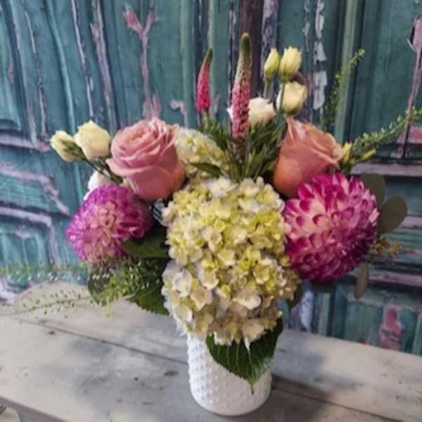 Mixed bouquet with roses, hydrangea, and dahlias in a white vase