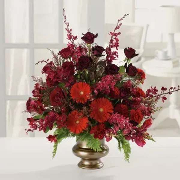 Red roses and orange gerbera daisies in a gold vase