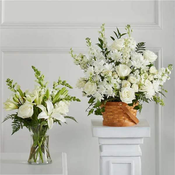 Two white floral arrangements, one in a glass vase and one in a basket.