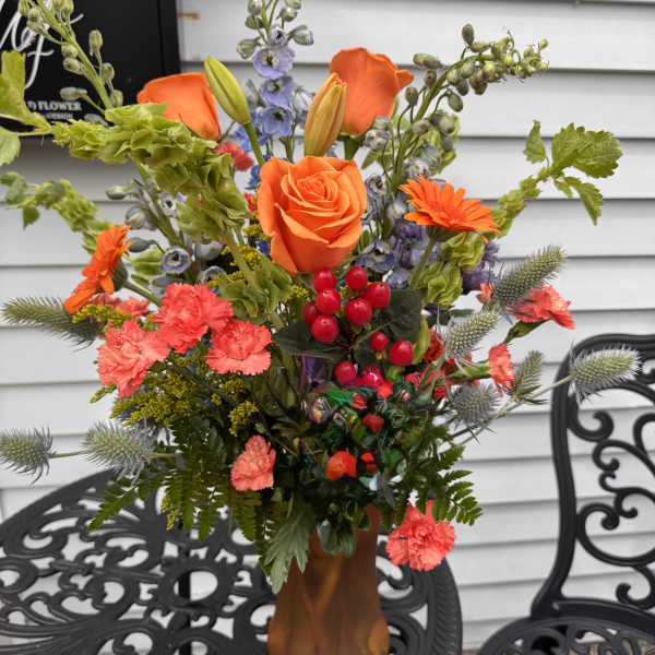 Orange roses and mixed flowers arranged in a vase.