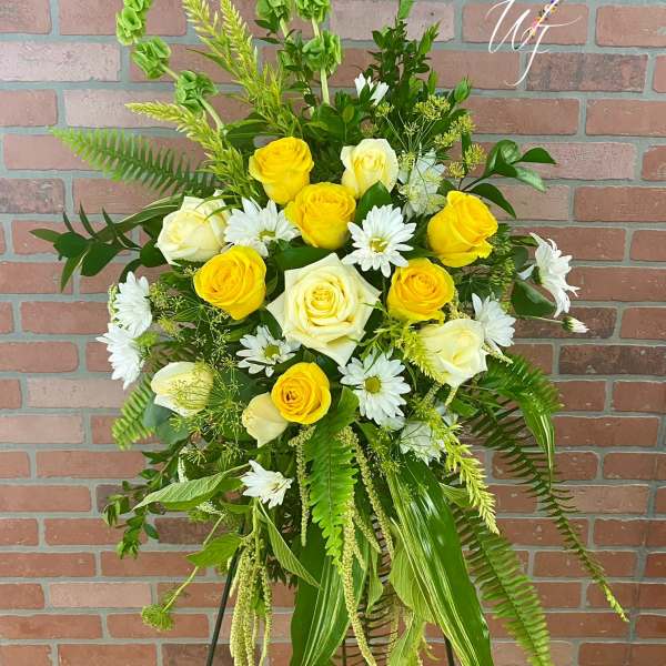 Yellow and white rose arrangement with daisies on a standing easel